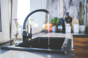 Black kitchen sink with water running.