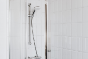 Close up of shower head with white tile behind it.