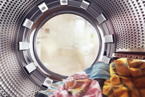 Inside view of a washing machine with a pink, yellow, and blue article of clothing sitting inside it.